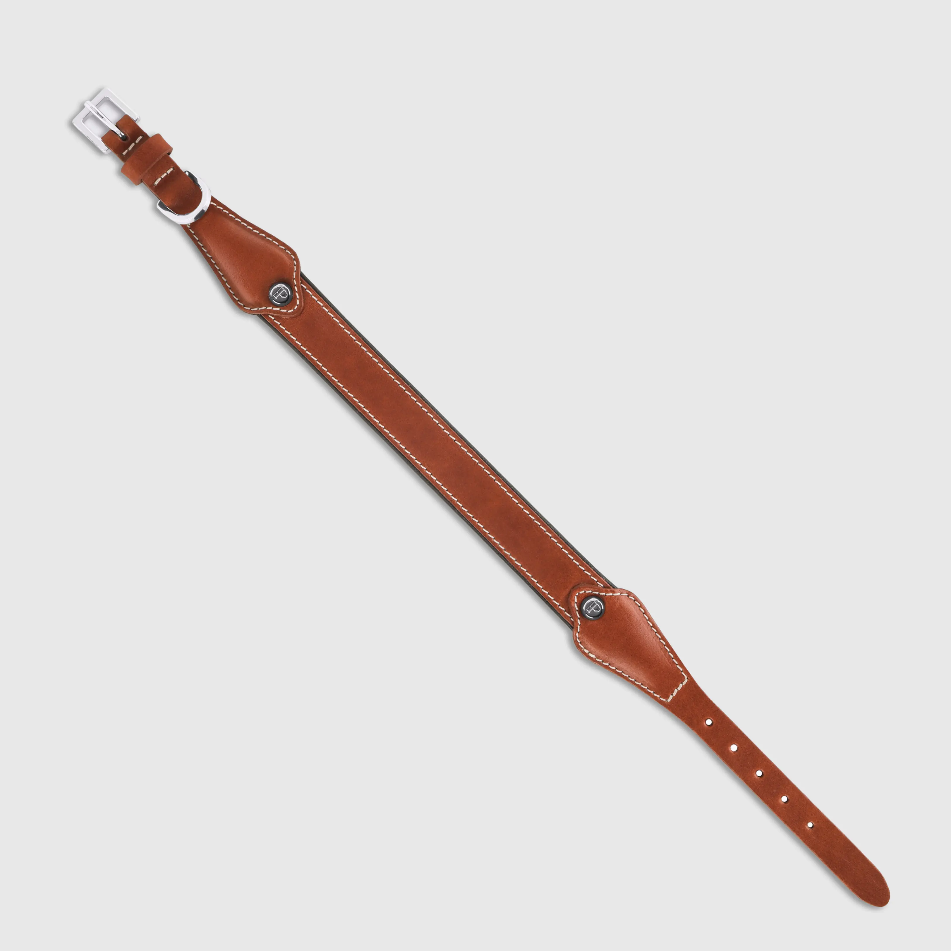 Hand-stitched from smooth, natural calfskin in an artisan workshop in the EU. Characterized by Pattmond’s signature shape, distinguished by subtle shifts in width and refined ornamental details. Caramel-coloured, vegetable-tanned leather exterior with beige contrast stitching and a brown leather lining. Solid brass hardware in silver (D-ring for the leash, buckle and signature logo studs), nickel-free and protected with a durable, polished finish. Adjustable length (see dimensions to choose the best fit for your dog). Available individually or in a set with a matching leather leash and gloves (made from lambskin).